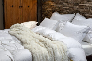 Páperové periny a vankúše rozložené na posteli – prirodzený spánok v jemných a nadýchaných perinách z prírodného páperia.